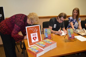 Suzanne & Paul Henry signing books as Lauren looks on website